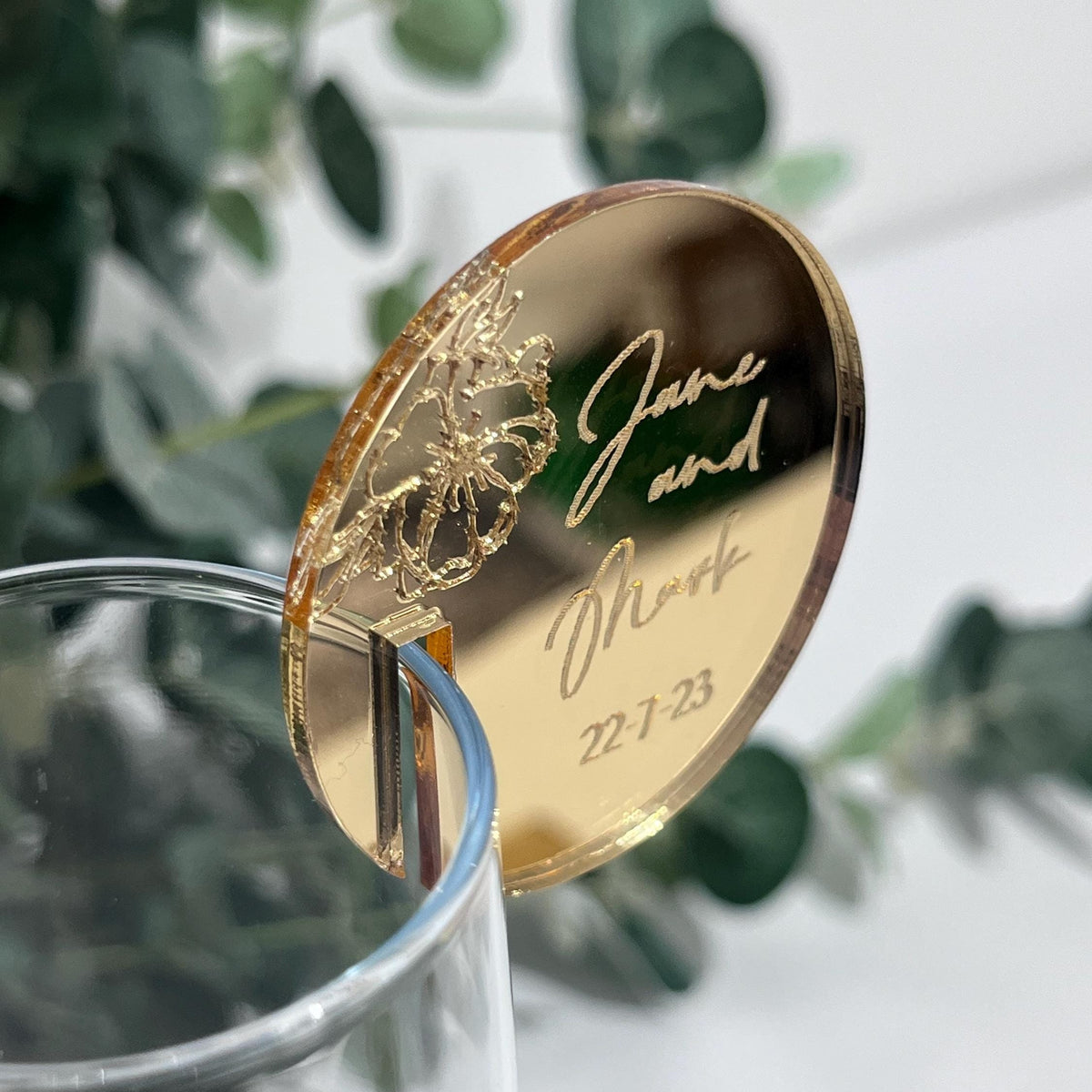 A mirror gold wedding place setting with engraved peony detail and bridal couples names and wedding date.