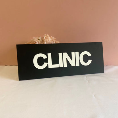Engraved black acrylic business sign, with CLINIC engraved and filled in white