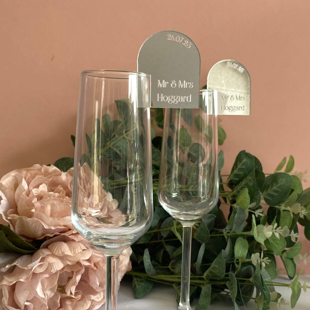 Mirror silver engraved acrylic wedding place settings displayed on champagne glassess