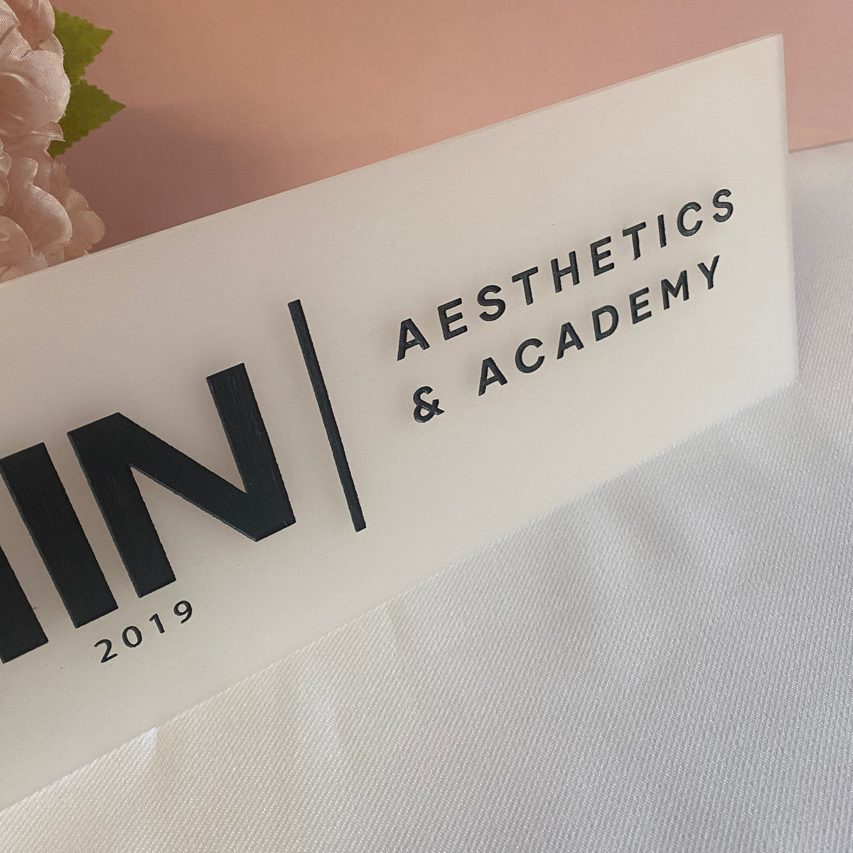 Close up of engraved business sign in frosted white acrylic with black engraved details