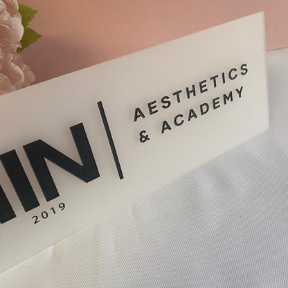 Close up of engraved business sign in frosted white acrylic with black engraved details