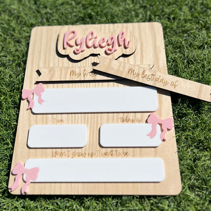 A personalised wooden back to school board with pink bow details and white reusable writing spaces.