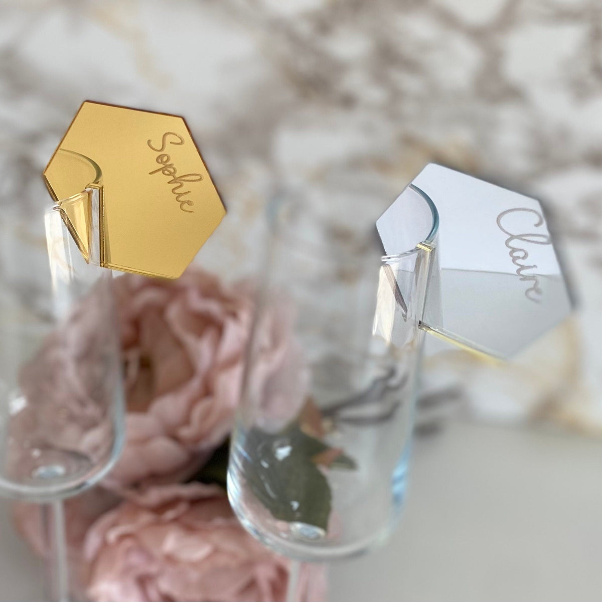 Hexagonal name tags on clear glasses with pink flowers in the background