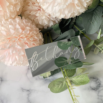 Engraved Wedding Place Name with 'Bethany' on a marble surface with flowers and leaves.