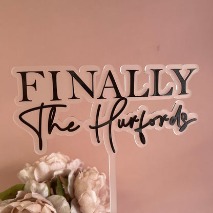 Wedding cake topper made with 2 layers of acrylic with the wording Finally the and the couples surname.