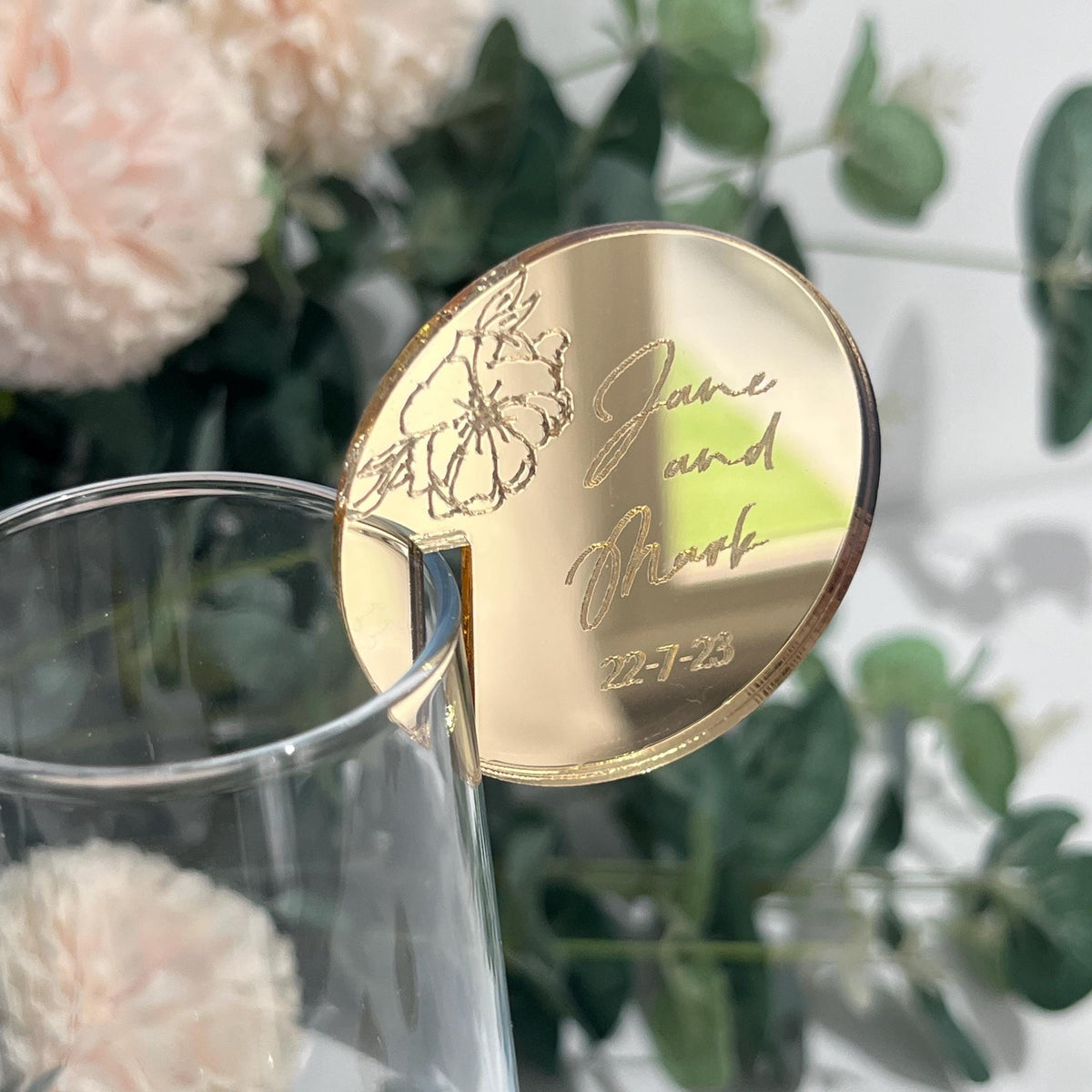 A mirror gold wedding place setting with engraved peony detail and bridal couples names and wedding date.