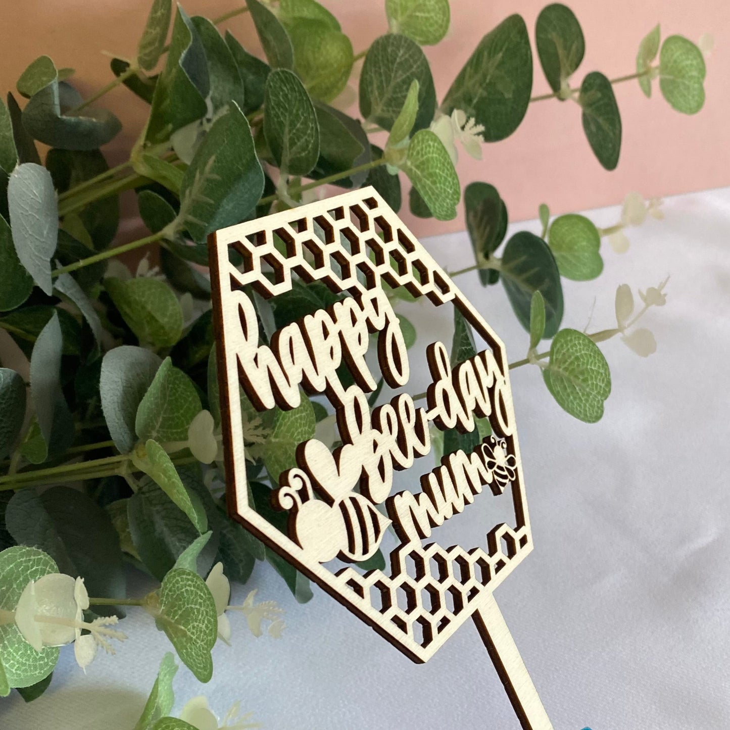Wooden Cake Topper in a hexagon shape with honeycomb and bee details.
