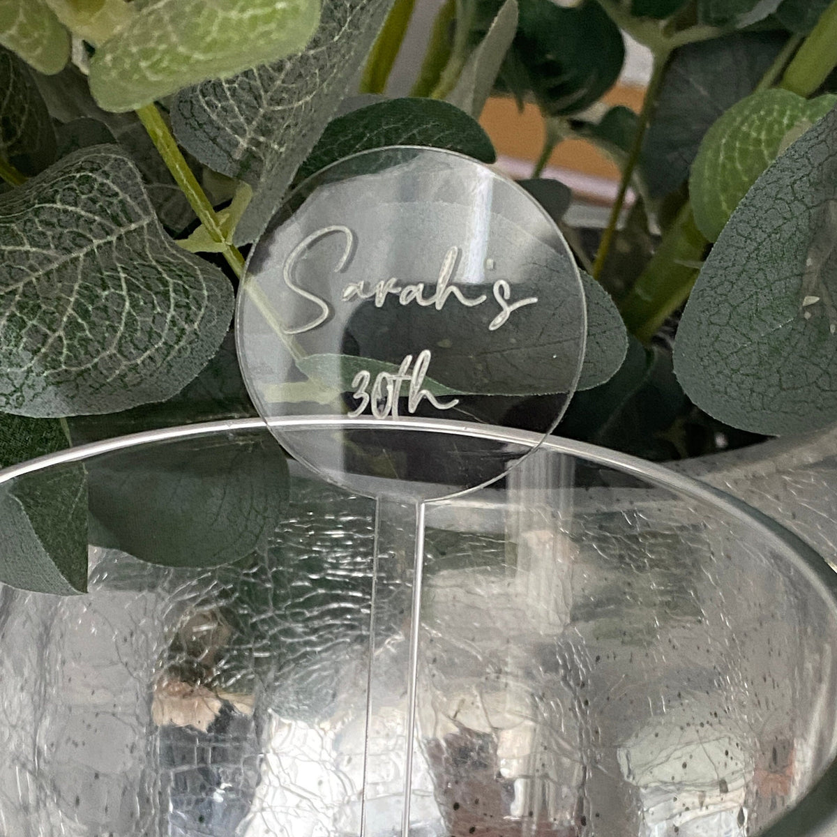 Clear acrylic cocktail stirrer with 'Sarah's 30th' engraved, placed in a glass