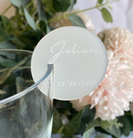 Personalized wine glass marker with 'Julian' and date, surrounded by flowers and greenery