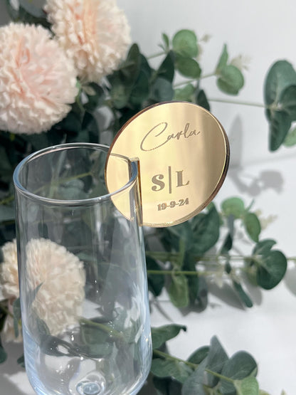 Gold mirror acrylic round Wedding Place Setting Glass Charm with personalised text on a glass with flowers and greenery in the background