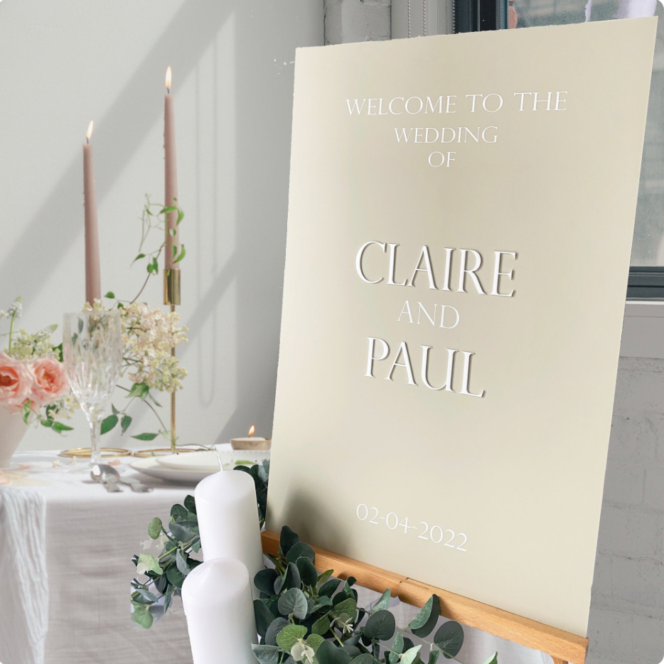 Wedding welcome sign for Claire and Paul with floral decorations and candles in the background.