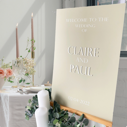 Wedding welcome sign for Claire and Paul with floral decorations and candles in the background.