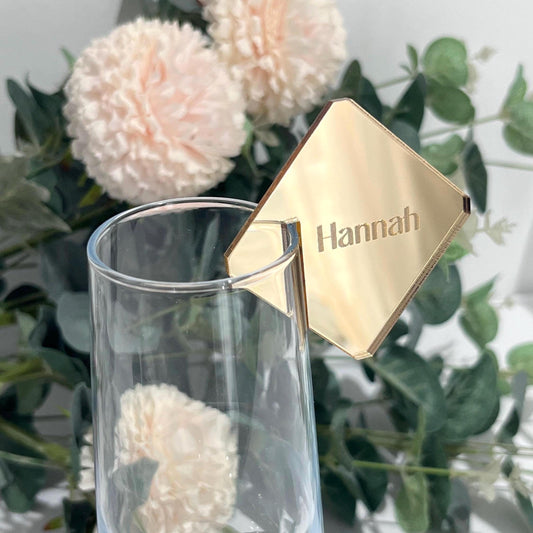 Gold Wedding seating chart Name with 'Hannah' on a glass with flowers in the background